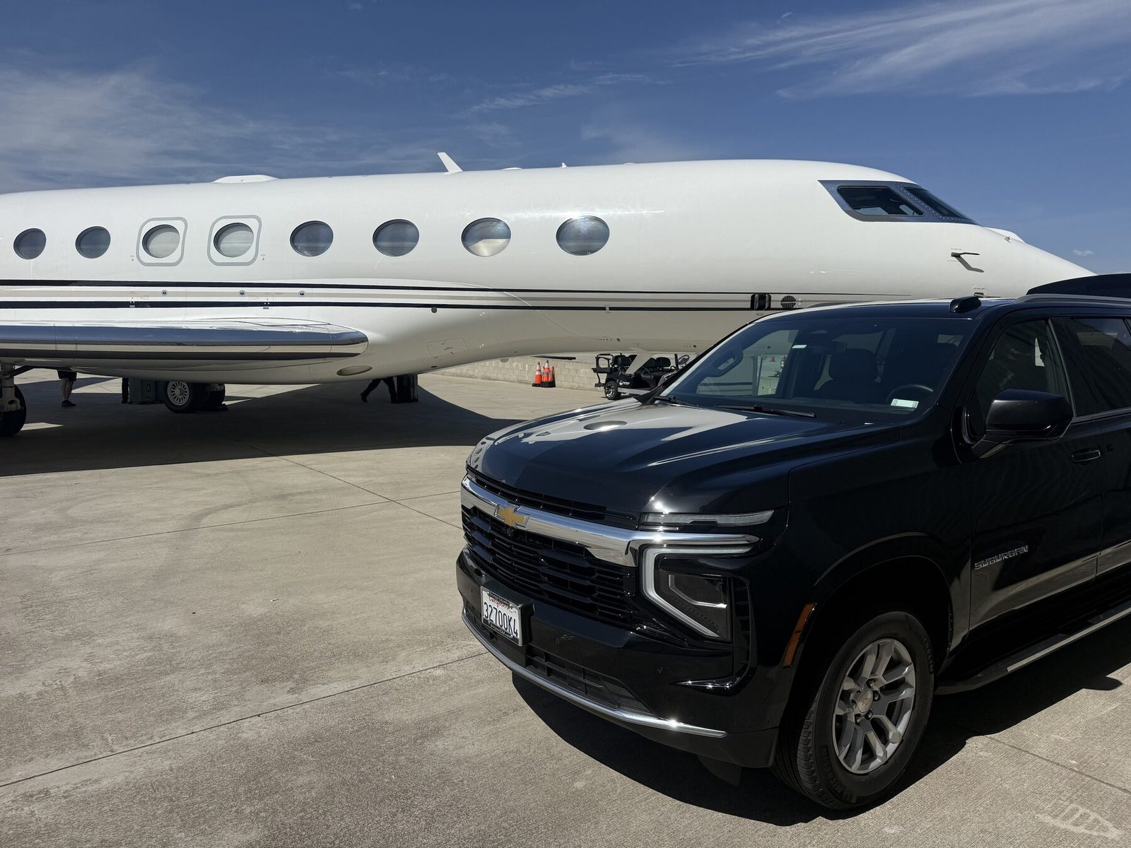 Blue Skies Chauffeured Transportation executive SUV parked on the tarmac beside a private jet, ready for an airport transfer