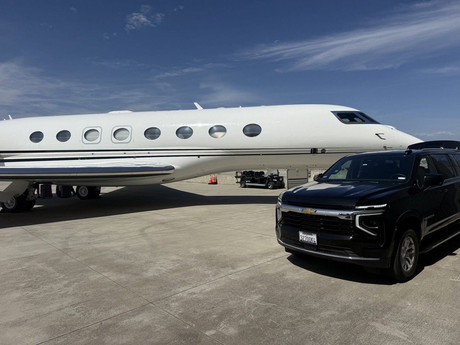 Blue Skies Chauffeured Transportation executive SUV on the tarmac beside a private jet