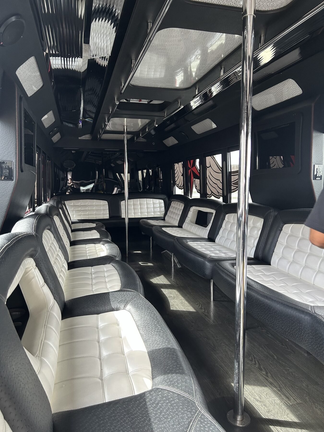 Interior of a larger party bus with black & white leather perimeter seating, LED lighting and skylight