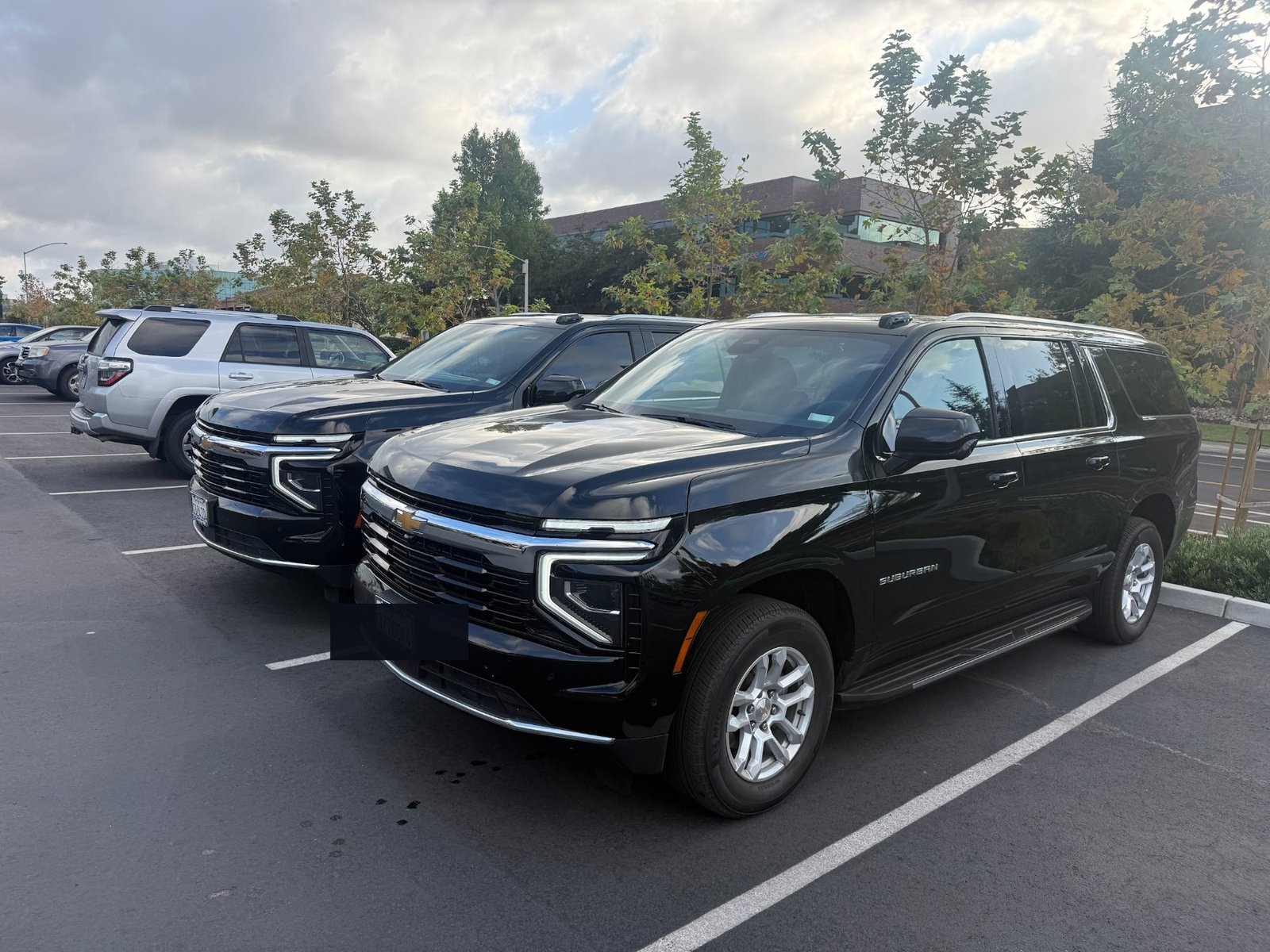 Two of Blue Skies Chauffeured Transportation's black Chevrolet Suburban SUVs parked side by side